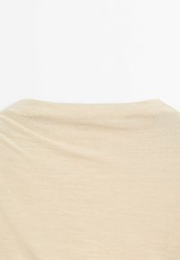 Beige lightweight knit fabric with a soft texture, displaying a subtle, flowing design and a rounded neckline.