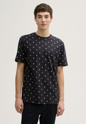 Camiseta negra de manga corta hecha de algodón, con un patrón blanco de hojas en toda la prenda. Cuello redondo clásico y corte relajado.