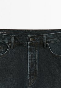 Mørke indigoblå denimjeans med knaplukning, bæltestropper og forlommer, med en Massimo Dutti-mærkat inde i linningen.