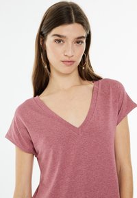Bordová v-neck tričko z mäkkej, ľahkej látky s krátkymi rukávmi a uvoľneným strihom, s hladkou textúrou a minimálnym zdobením.
