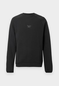 Sudadera negra de cuello redondo Reebok con mangas largas y pequeño logo reflectante centrado en el pecho, sobre fondo blanco liso.