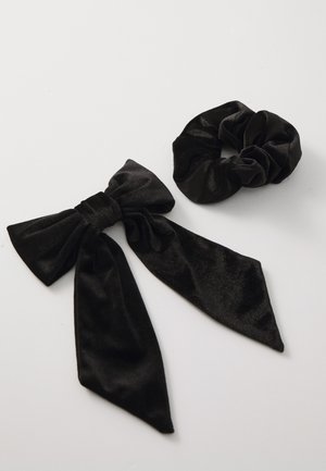 Must have siidised juukseaksessuaarid: suur lips pikade saba ja sobituv scrunchie. Mõlemad omavad pehmet ja siledat tekstuuri.