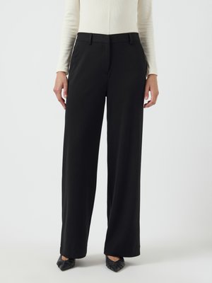 Black wide-leg trousers with a smooth texture. Features a fitted waist and front pockets. Paired with pointed black shoes.