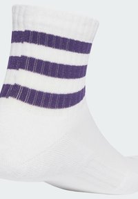 Calcetines de algodón hasta el tobillo con una base blanca y franjas moradas llamativas. La textura es acanalada cerca del puño, y la forma general es ajustada.