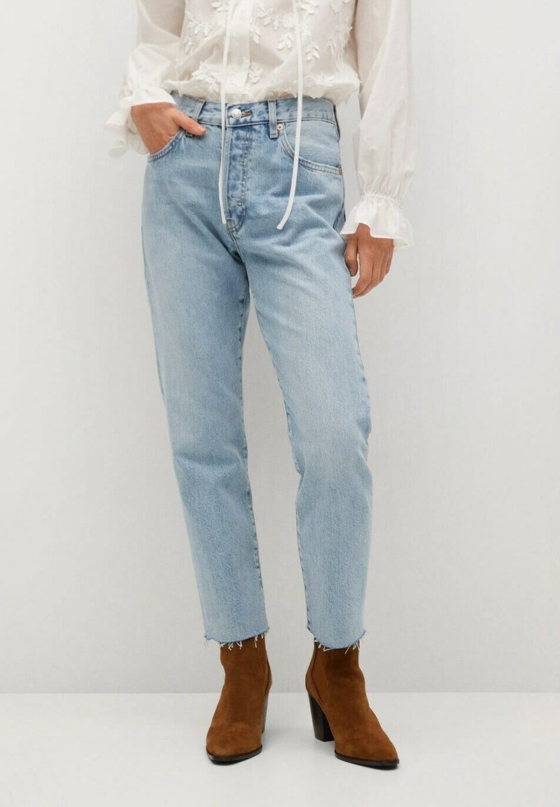 Jean bleu clair taille haute avec une coupe droite, ourlet effiloché et design classique à cinq poches, assorti à des bottines marron.