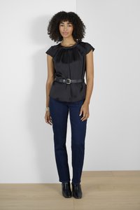 Blouse en satin noir avec un col plissé, associée à un jean bleu foncé et des bottines noires. Présente une taille cintrée et des manches courtes.