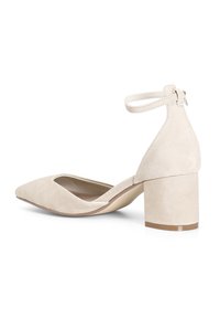 Scarpa con tacco a blocco in suede beige, punta affusolata e cinturino alla caviglia. Presenta una texture liscia e una soletta leggermente imbottita.