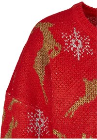 Czerwony sweter dziany z wzorami w złotej i białej kolorystyce przedstawiającymi renifery. Materiał jest miękki, ma klasyczny okrągły dekolt i prążkowane wykończenia.