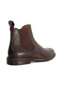 Brown leather Chelsea boot with elastic side panel, round toe, and pull tab. Smooth texture, low stacked heel. No visible patterns or accents.
