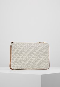 Witte handtas met een herhalend lichtgrijs "MK" patroon, bruine leren afwerking, rechthoekige vorm en een rits in goudkleur.