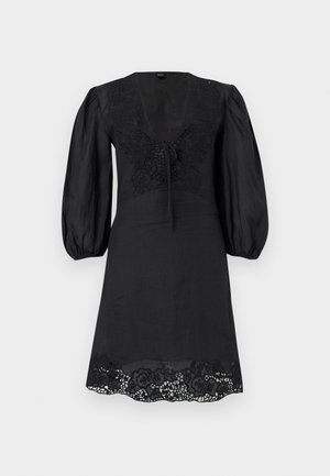 Zwarte knie-lange jurk met opgepofte driekwartmouwen, V-hals met strik, bloemenkant details op borst en zoom.