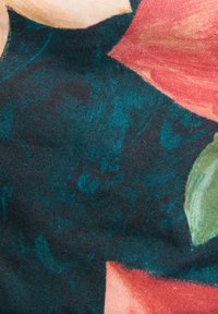 Σκούρο τιρκουάζ ύφασμα με κόκκινα και πράσινα λουλουδάτα σχέδια και υφασμένη υφή σε κοντινή απόσταση.