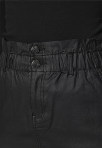 Pantalons en simili cuir noir et brillant avec une taille élastique froncée, dotés de deux boutons avant et de coutures sur les côtés.