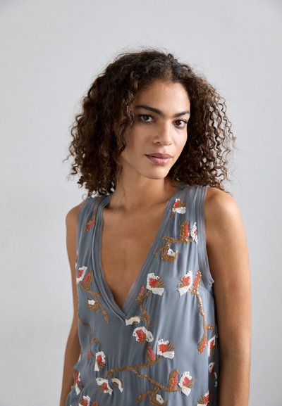 Hallideh/õlata korraline hall kleit, millel on punane, valge ja kuldne lilleline tikand. Sügava V-kaelusega ja voolava, pehme tekstuuriga.