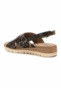 Sandalía de estampado de leopardo con diseño abierto, una correa de cuero marrón en la parte trasera y una suela de plataforma beige ligera. Material superior texturizado.