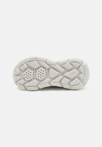Zool van een sneaker, gemaakt van een gestructureerd wit rubbermateriaal met een hexagonaal patroon en ventilatiegaten voor ademend vermogen.
