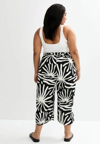 Schwarz-weiße, gemusterte Culotte-Hosen mit fließendem Design und elastischem Bund, die mutige abstrakte Formen und eine kurze Länge aufweisen.