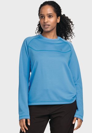 Blaues Langarm-Sweatshirt mit rundem Halsausschnitt, strukturiertem Stoff und kontrastierenden Nähten. Getragen mit schwarzen Hosen.