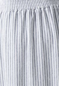 Tela ligera a rayas con una mezcla de tonos azules y blancos. Presenta una cinturilla fruncida y una superficie texturizada con líneas verticales.