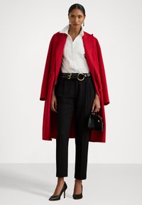 Piros gyapjúkabát, fehér csíkozott ing, fekete nadrág és fekete magassarkú cipő. Arany csatos fekete övet és egy kis fekete táskát tartalmaz.