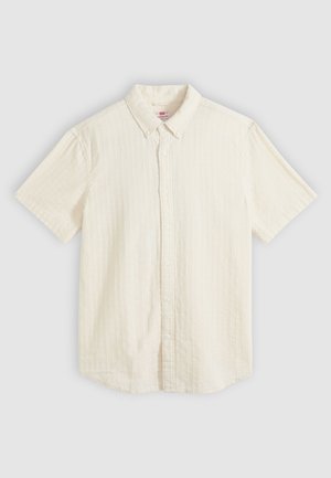 Chemise beige à manches courtes avec boutons, col et texture subtile à rayures verticales, posée à plat sur un fond neutre.