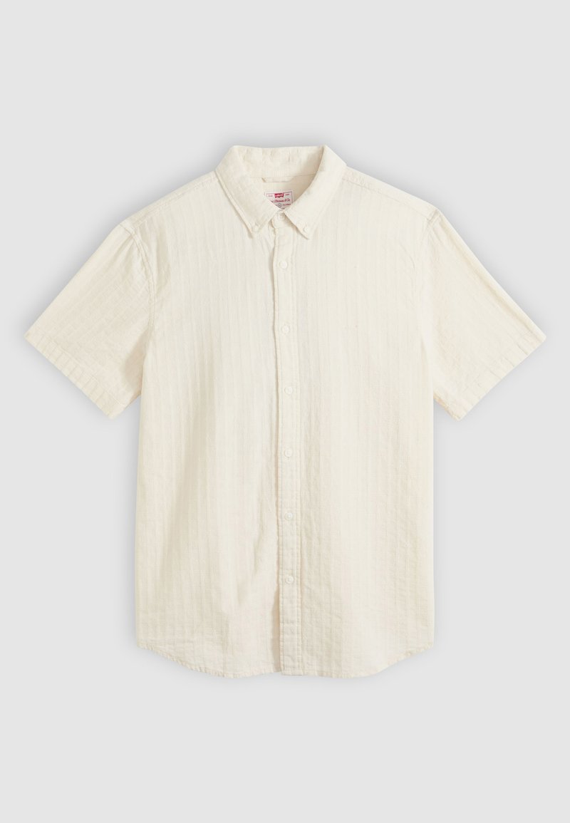 Chemise beige à manches courtes avec boutons, col et texture subtile à rayures verticales, posée à plat sur un fond neutre.