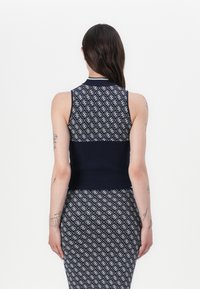 Haut sans manches bleu marine au design ajusté, présentant une texture tricotée à motifs et une bande unie bleu marine à la taille, affiché de dos.