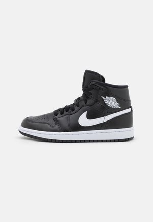 Czarno-biały wysokiej klasy sneaker Air Jordan z czarnymi sznurowadłami, perforowanym noskiem i białym logo Nike po stronie na jednolitym tle.
