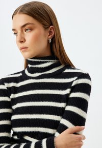 Gestreifter Rollkragenpullover in Schwarz und Weiß, aus weichem, strukturiertem Stoff, mit horizontalen Streifen und taillierter Form.