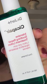 Dr. Jart+ Cicapair beroligende lotion i en gjennomsiktig flaske med en blågrønn topp. Etiketten har hvit og rosa tekst. Inneholder 150 ml.