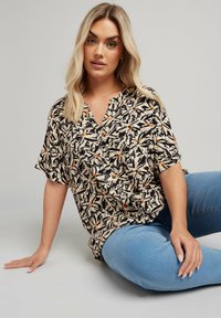 Blusa nera e crema a maniche corte con scollo a V, decorata con un motivo di foglie e uccelli con accenti arancioni. Tessuto leggero, vestibilità comoda.