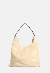 Beige leren hobo tas met een gebogen vorm, glanzende textuur en een afneembare zwarte riem met goudkleurige metalen accenten.