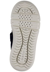 Bílá gumová podešev s texturovaným vzorem, vybavená odvodňovacími otvory pro prodyšnost. Boční design zahrnuje námořnické tkaninové akcenty.