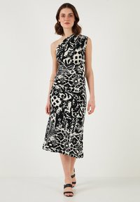 Asymmetrical black-and-white dress with abstract patterns, fitted bodice, and mid-length skirt. Smooth fabric with one shoulder design.