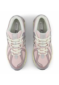 Lichtroze sport schoenen met een bovenwerk van mesh, witte veters, zilveren accenten en een gele middenzool. Bevat een logo op de tong en de zijkanten.