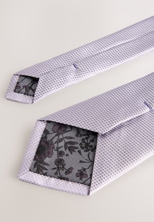 Svetlo vijoličen teksturiran kravata z diamantnim vzorcem, ki ima črto cvetlične mreže na koničastih koncih. Gladek zaključek tkanine.