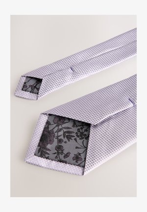 Světlofialová texturovaná kravata s diamantovým vzorem, na špičatých koncích černá květinová síťovaná podšívka. Hladký povrch látky.
