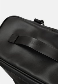 Borsa sintetica nera con una texture liscia, dotata di un manico piatto impresso con "KIWEE" e un design minimalista.