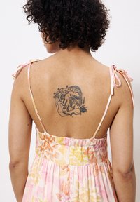 Robe d'été à motifs floraux avec des teintes de rose, jaune et orange. Dotée de bretelles spaghetti, d'un dos smocké et d'un tatouage dans le haut du dos.