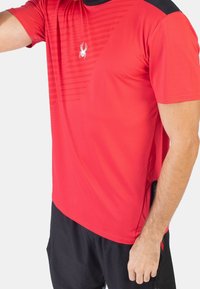 Rode sportieve t-shirt met korte mouwen, voorzien van een getextureerd diagonaal streepdesign, klein logo op de borst en zwarte accenten op de schouders.