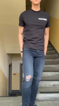 Νέος άνθρωπος κατεβαίνει εσωτερικές σκάλες φορώντας ένα μαύρο t-shirt Replay και σκισμένο μπλε τζιν.