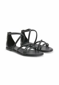 Sandales plates noires avec plusieurs designs de lanières, présentant une texture en cuir lisse et une fermeture à glissière à l'arrière.