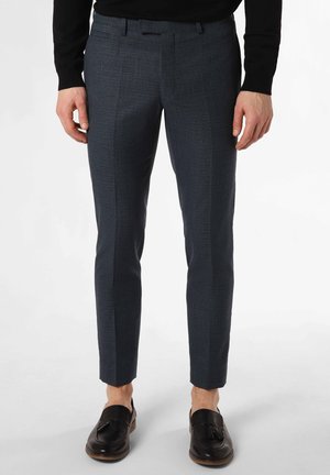 Angepasste marineblaue Hose aus strukturiertem Stoff, schmaler Schnitt und mit eingeprägtem Bund. Getragen mit schwarzen Slippern und in verkürzter Länge.