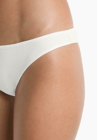 Wit geribbeld bikinionderstuk met een gladde textuur, voorzien van een middelbrede tailleband en een minimalistisch ontwerp.