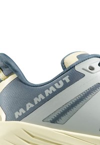 Lättviktsvandringsskor med en mörkblå texturerad ovandel, krämfärgade accenter och en framträdande "MAMMUT"-logotyp, med en dämpad häl för komfort.