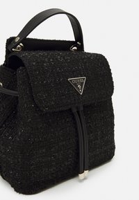 Sac à dos en tweed noir à la forme structurée, doté d'un rabat repliable, d'une poignée en cuir noir et de détails en logo en argent.