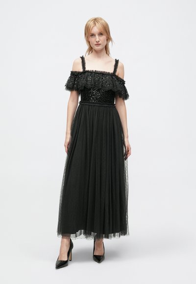 Robe noire décolletée avec un corsage en sequins et une jupe en tulle superposée. Comprend des bretelles frisées et une silhouette fluide.