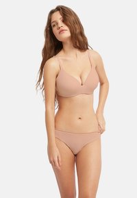 Ensemble de soutien-gorge et de bikini en tissu lisse de couleur chair, avec des bretelles réglables et des coutures minimales pour un look sans couture. Design léger et ajusté.