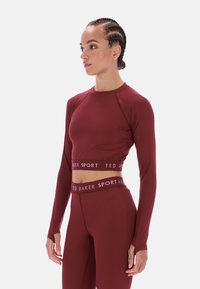 Bordó hosszú ujjú sportos rövid felső lekerekített nyakkivágással és kontrasztos szegéllyel, amelyen a "TED BAKER SPORT" felirat található az alsó szegélyen.