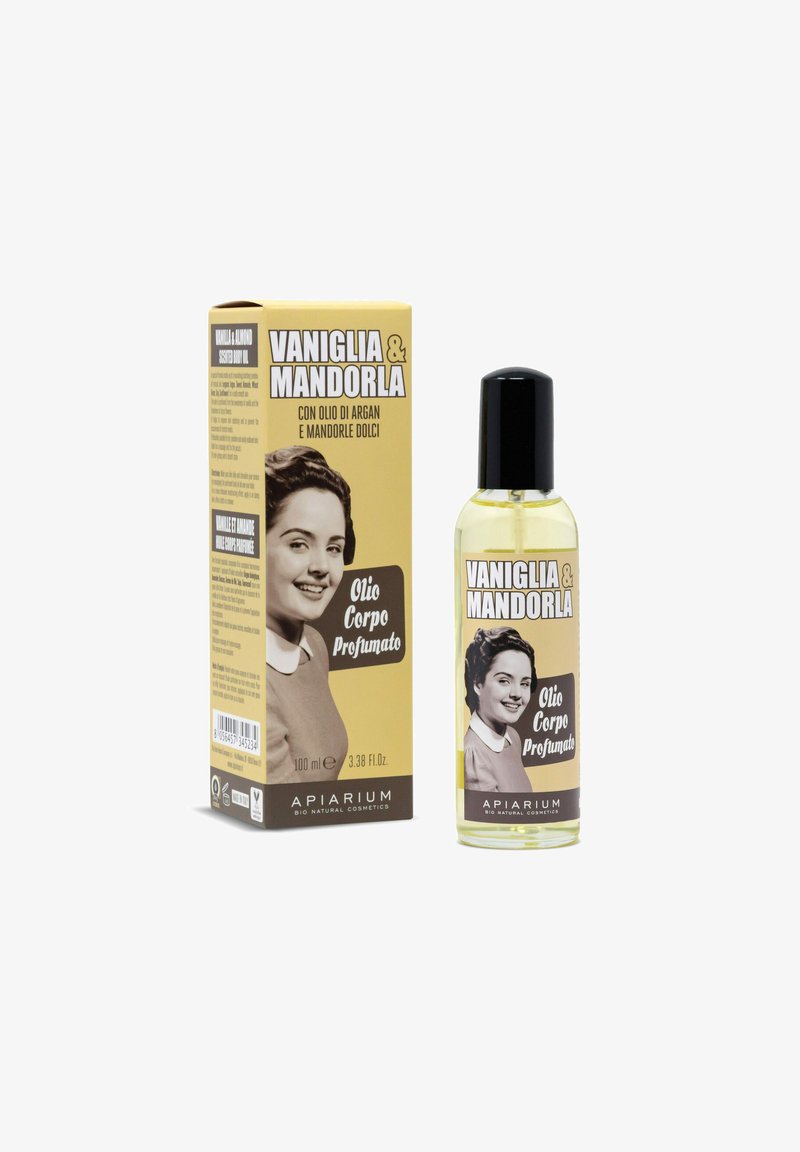 Olio di profumo in una bottiglia trasparente con un tappo nero. La scatola è beige con una foto vintage e testo in grassetto. Contiene vaniglia e mandorla.